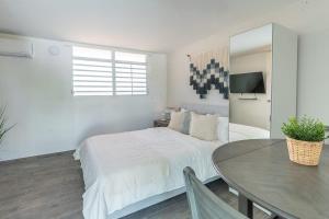 a white bedroom with a bed and a table at AQUA Terrazas Studio 5 - Oceanfront, Pool & Local Dining in Mameyal +11 photos