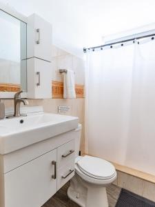 een witte badkamer met een wastafel en een toilet bij AQUA Terrazas Studio 5 - Oceanfront, Pool & Local Dining in Mameyal +16 foto's