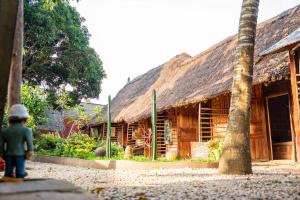 a house with a thatched roof with a child standing in front of it at Le Jardin Secret in Ouidah