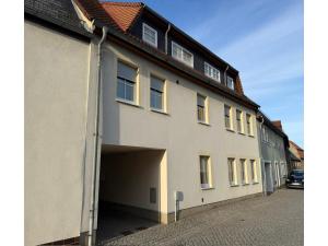 a large white building with a garage next to a street at Moderne Ferienwohnung in Elstra in Elstra