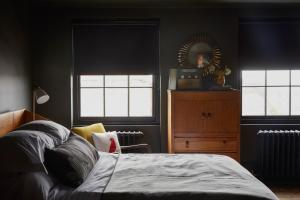 a bedroom with a bed and two windows and a dresser at Smiths Townhouse in Broadstairs