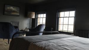 a bedroom with a bed and two chairs and windows at Smiths Townhouse in Broadstairs +6 photos