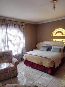 a bedroom with a large bed and a chair at Sonnic Motel in Benoni