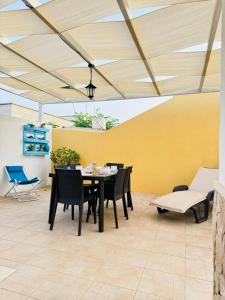 un patio con tavolo e sedie e un muro giallo di Casa Vacanze Mareblù ad Alliste