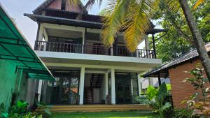 ein Haus mit einem Balkon darauf in der Unterkunft Mango Lantern Villa by Mirth, Kollam in Perumanseri