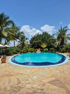 a swimming pool in a resort with palm trees at African Dream Cottages - Diani Beach in Diani Beach