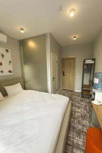 a bedroom with a large white bed and a television at Unit Hotel in Almaty