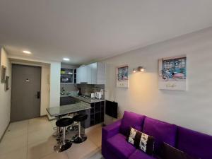 a living room with a purple couch and a kitchen at Apart Lomas de San Andres CENTRO in Concepción