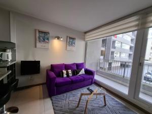 a purple couch in a living room with a window at Apart Lomas de San Andres CENTRO in Concepción