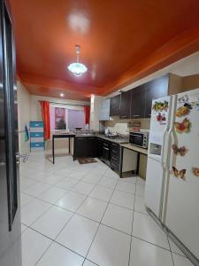 eine große Küche mit weißen Fliesenböden und Geräten in der Unterkunft Fade House in Temara