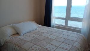 a bedroom with a bed and a window with the ocean at departamentoplaya in Tomé