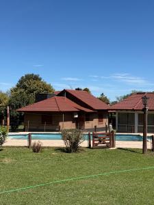 a house with a swimming pool in front of it at Cabañas Lomas del mirador in Villa del Dique