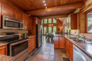 a kitchen with wooden cabinets and stainless steel appliances at Private A-Frame Log Cabin near Tremblant With Hot tub Game Room in Labelle