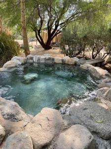 a hot spring with rocks in a garden at Reserve The Entire Ranch up to 28 guests in Desert Hot Springs