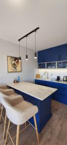 a kitchen with blue cabinets and a counter with chairs at Mint 2 in Veliko Tŭrnovo