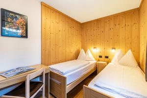 two beds in a room with wooden walls at Villa Erina App C3 in Ortisei
