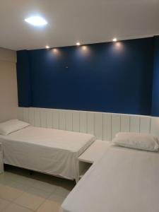 Cette chambre comprend 2 lits et un mur bleu. dans l'établissement Beverlly Hills, à Aquiraz