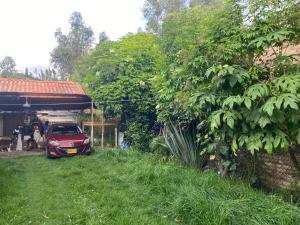 une voiture rouge garée dans une cour à côté d'une maison dans l'établissement Cabaña Emanuel, à Paipa