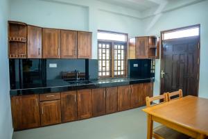 a kitchen with wooden cabinets and a wooden table at Backpackers GuestHouse Trincomalee in Trincomalee