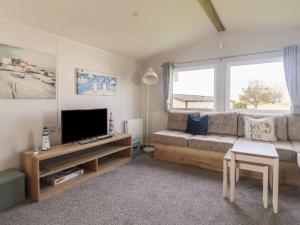 a living room with a couch and a tv at 39 Greenlands, Littlesea Holiday Park in Wyke Regis