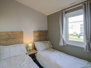 two beds in a small room with a window at 39 Greenlands, Littlesea Holiday Park in Wyke Regis