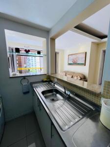 Guarujá Golden Beach 158 - Conforto com Piscina Climatizada في غوارويا: مطبخ صغير مع حوض ونافذة