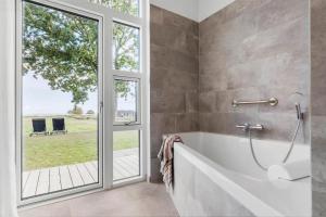 un bagno con vasca e una grande finestra di 8959-Orsted-Klydevej-9 a Estruplund Altre 18 foto