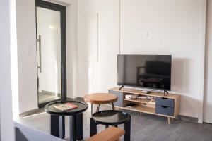 Una sala de estar con dos taburetes y un televisor de pantalla plana. en Villa Colibri au coeur de l'île, piscine privé, en Les Abymes