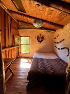 a bedroom with a bed in a wooden cabin at Cabaña de barro con Bosque, rio, arte y apicultura in Epuyén