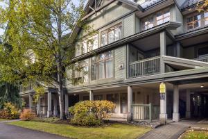 a large house with a tree in front of it at Steps From The Village with Pool and Hot Tub by Harmony Whistler in Whistler