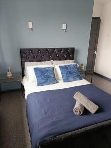 ein Bett mit einer blauen Decke und einem Hut darauf in der Unterkunft #72 Stylish 3 bedroom sleeps 7 Wigan House in Pemberton