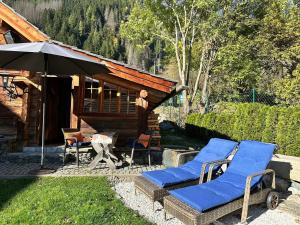 a couple of chairs and an umbrella in front of a cabin at Romantikhütte in Flattach