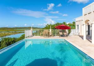 einen Pool mit einem Tisch und einem Sonnenschirm in der Unterkunft Breathtaking Chalk Sound Private Pool Sunset Villa in Providenciales