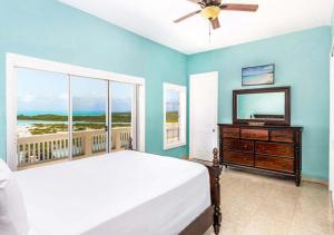 ein Schlafzimmer mit einem Bett und einem Fernseher und einem Fenster in der Unterkunft Breathtaking Chalk Sound Private Pool Sunset Villa in Providenciales + 21 Fotos