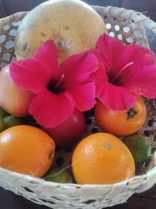 a basket of fruit with two pink flowers on top at Villa Ti Kabri, 500 m de la plage, Ile Rodrigues, Ile Maurice in Saint Francois