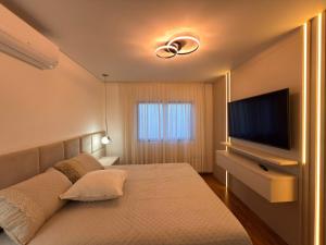ein Schlafzimmer mit einem Bett und einem Flachbildfernseher in der Unterkunft Lar doce lar, 300 metros do centro, 300metros do shopping in Pato Branco