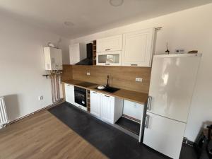 a kitchen with white cabinets and a white refrigerator at Bee apartman in Odorheiu Secuiesc