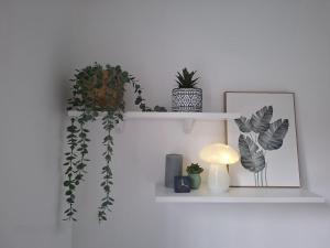 a white shelf with plants and a lamp and a picture at MJ Casa Vacanza Vicino Aeroporto Malpensa in Borsano