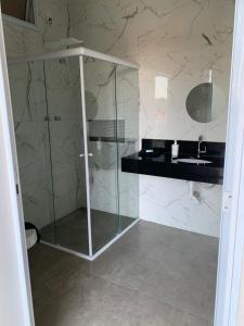a bathroom with a glass shower and a sink at Hospedaria Colinas in Indaiatuba