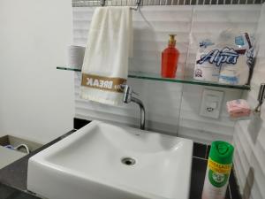a bathroom with a white sink and a shelf at Apartamento em Adrianópolis confortável in Manaus