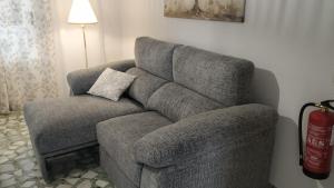 a gray couch sitting in a living room with a lamp at Flor de Almendro, cerca de Toledo y Puy du Fou in Portillo de Toledo