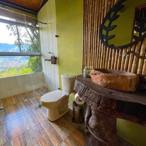 Un baño con inodoro, lavabo y ventana. en ANCESTRAL GLAMPING, en Barbosa