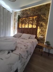 a bedroom with a bed and a stone wall at Casa rural La Pinada in Villanueva de Viver
