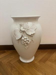 a white vase with flowers on it on a wooden floor at Minerva in Viareggio