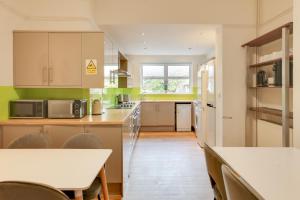 a kitchen with white cabinets and a table and chairs at NOW OPEN! Brand new rooms City Centre Modern Ensuite Rooms by Luxiety Stays in Cambridge
