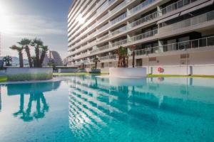 a large pool of blue water in front of a building at Lujoso Golden Sunset in Oropesa del Mar