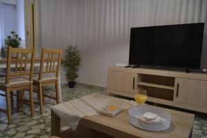 a living room with a television and a table with a glass of wine at Flor de Almendro, cerca de Toledo y Puy du Fou in Portillo de Toledo