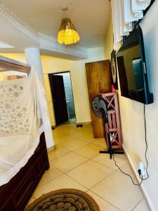 a room with a bed and a tv and a hallway at Jean pierre studio apartment in Malindi