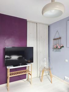 a living room with a tv and a purple wall at Grand duplex tout confort, à 2km de la Baie de Cancale - Mt St Michel in La Fresnais