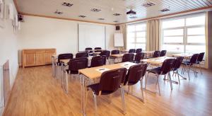 a classroom with tables and chairs and a whiteboard at Home Hotel With in Tromsø